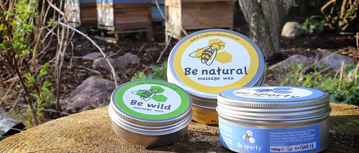 tins of massage wax with bee hives in the background